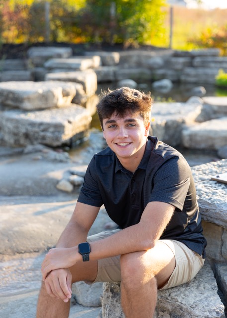high school senior boy sitting on a rocks at Summit Park Blue Ash Ohio