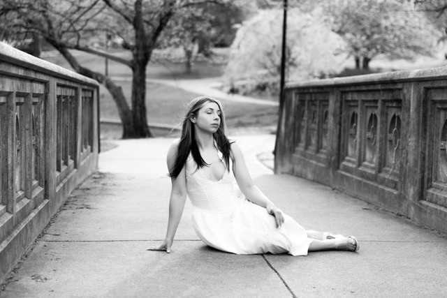 high school senior girl posing on bridge in white dress in Eden Park