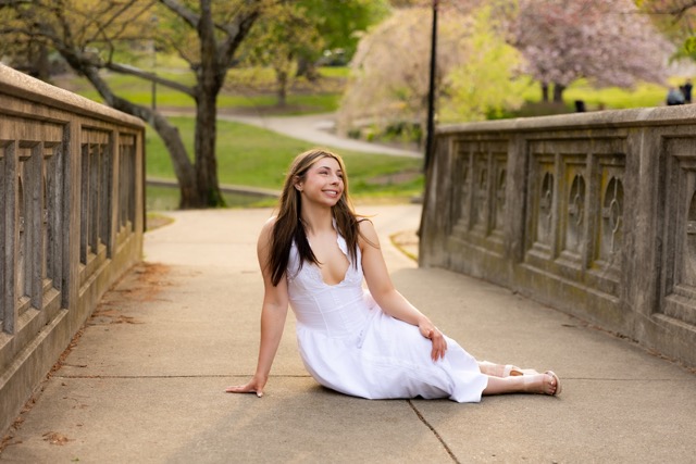 high school senior girl posing on bridge in white dress in Eden Park