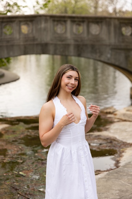 high school senior girl posing by the pond and bridge in white dress in Eden Park