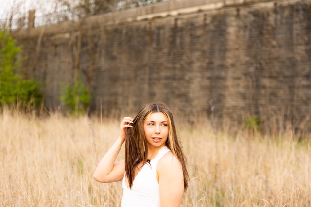 high school senior girl posing by wall in Eden Park