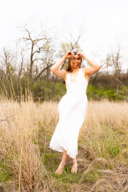 high school senior girl posing by tall grass in white dress in Eden Park