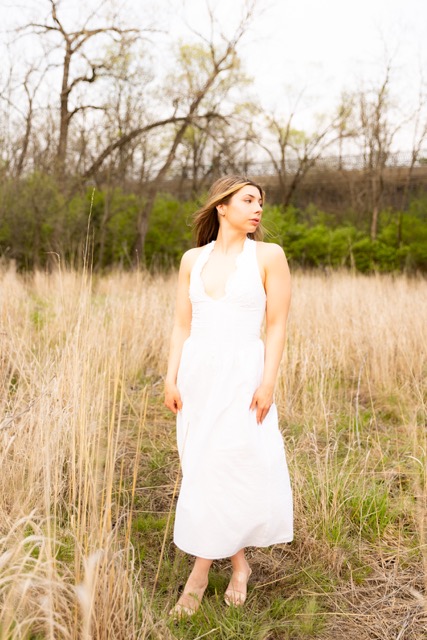 high school senior girl posing by tall grass in white dress in Eden Park
