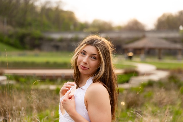 high school senior girl posing by tall grass in white dress in Eden Park