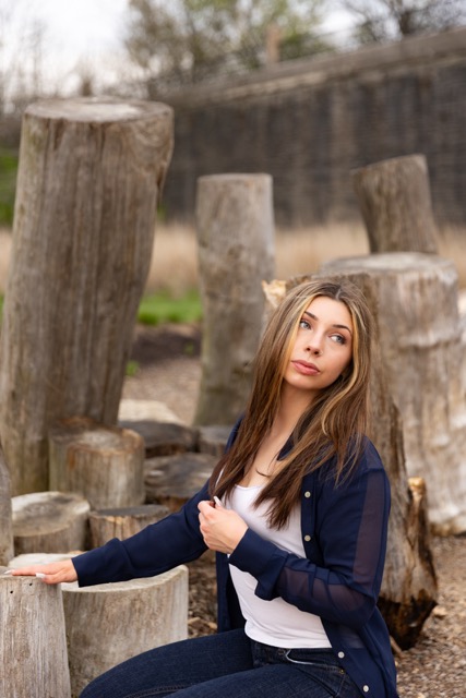 high school senior girl posing on a natural wood playscape