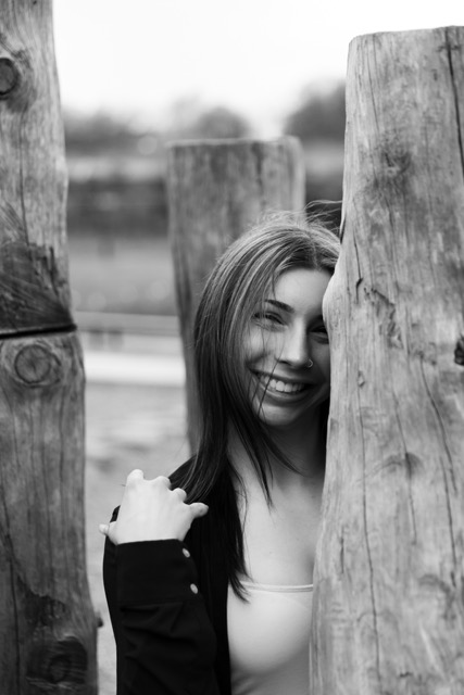 high school senior girl posing on a natural wood playscape