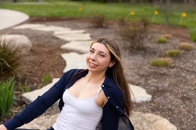 high school senior girl posing on a natural wood playscape