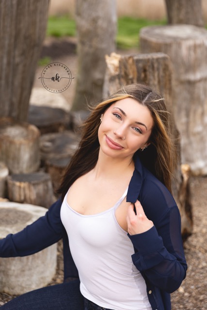 high school senior girl posing on a natural wood playscape