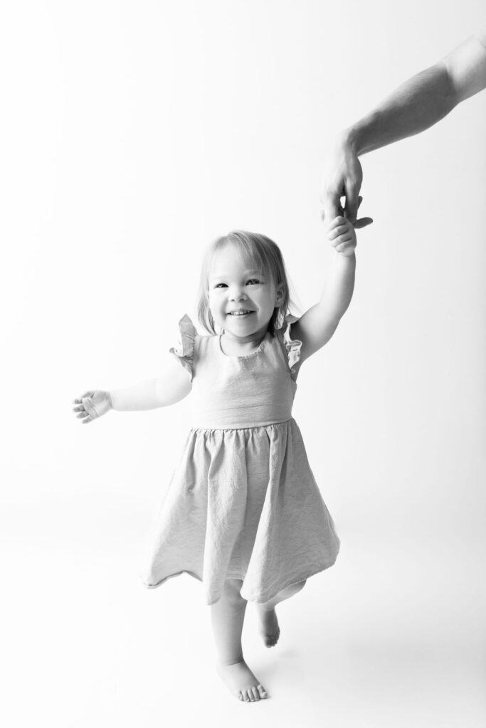 Toddler taking assisted steps with a helping hand from an adult.