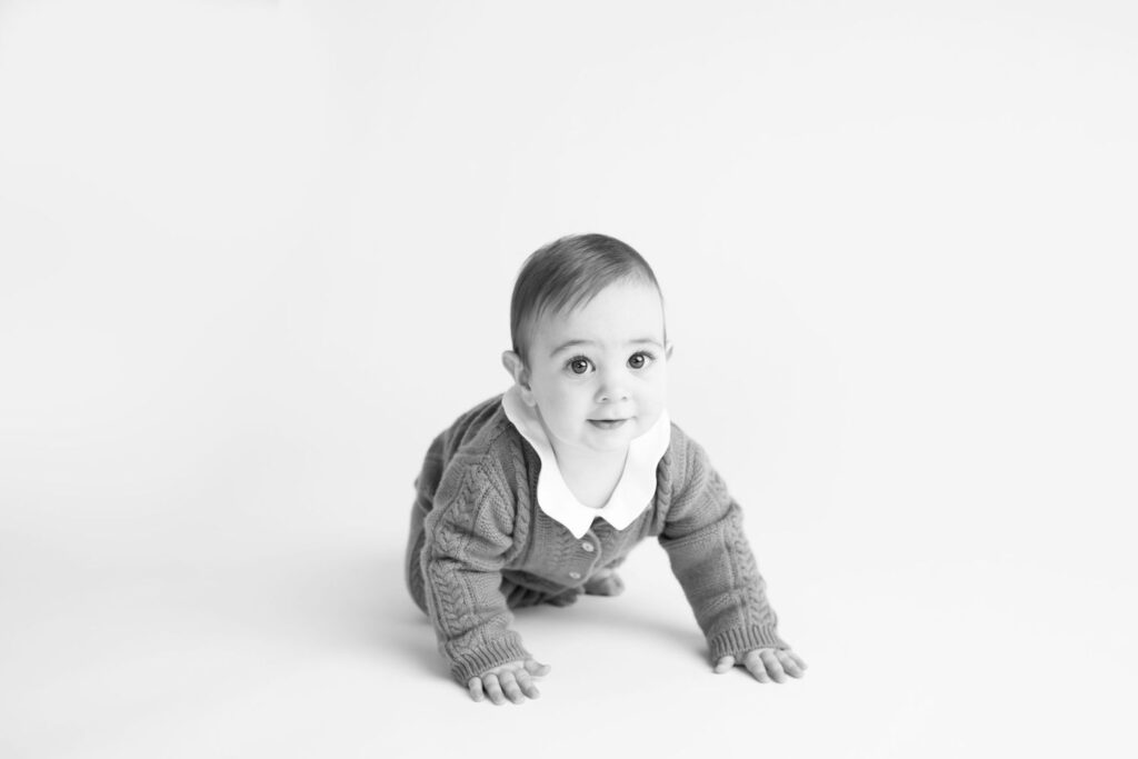 A black and white photograph of a baby crawling towards the camera with a curious expression.