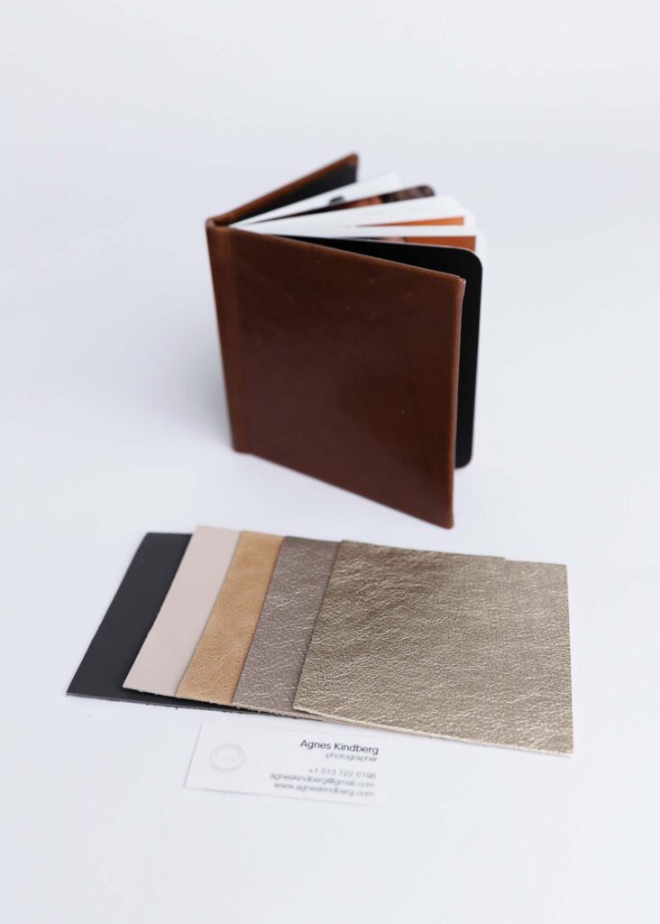 A leather wallet with multiple cards sticking out, placed next to sample swatches of fabric colors and textures, with a business card visible on the table.