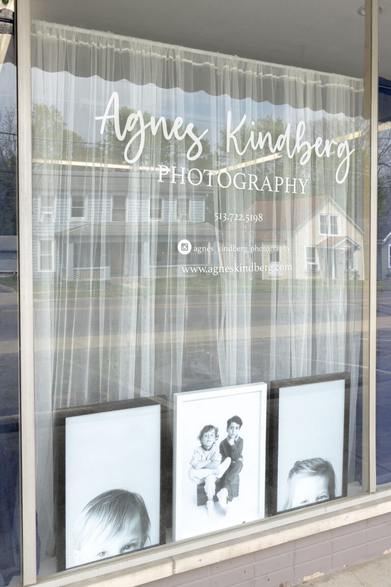 Storefront window showcasing a photography business with displayed portrait samples.