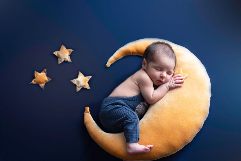 A sleeping baby cradled on a crescent moon pillow against a starry backdrop symbolizes fertility awareness.