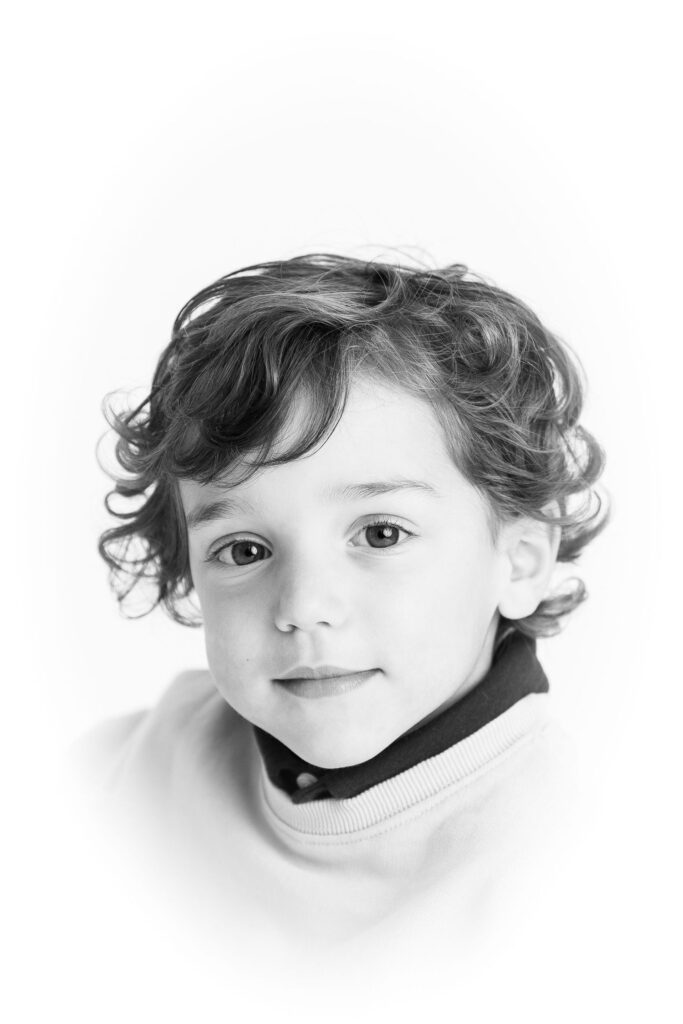 Portrait of a child with curly hair against a white background.