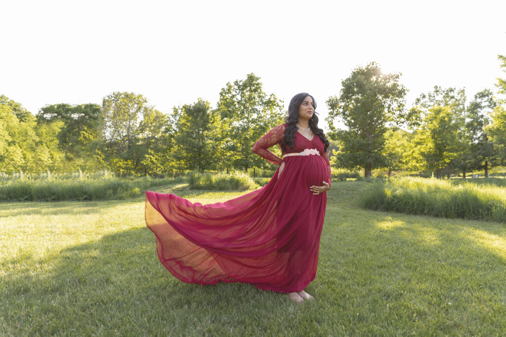 Pregnant woman posing in red dress outdoors