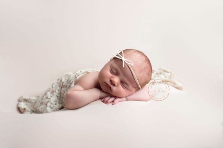 Newborn baby sleeping peacefully with a delicate headband.