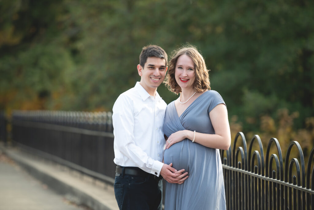 Expecting couple posing outdoors for maternity photoshoot.