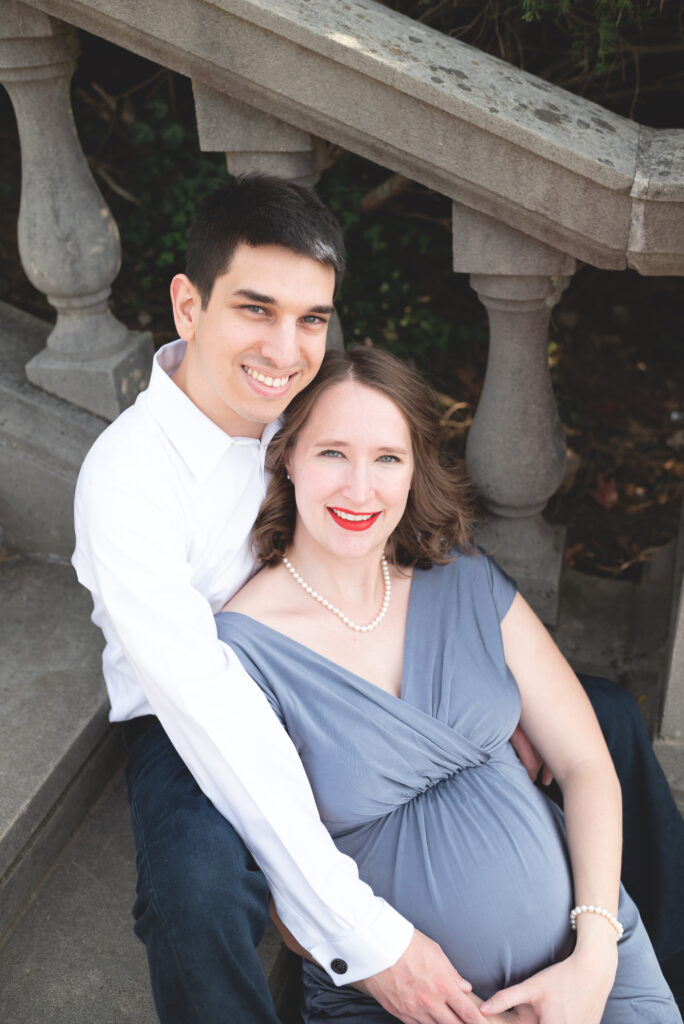 Couple during maternity photo shoot outdoors on steps.