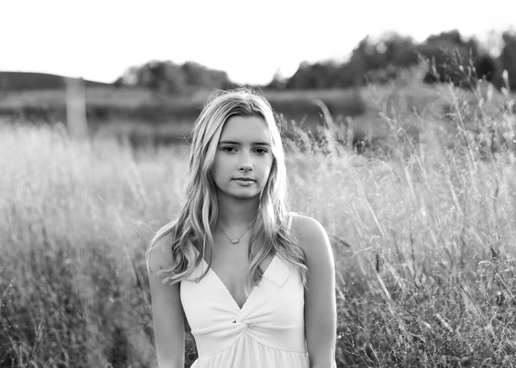 Young woman standing in field, black and white photo.