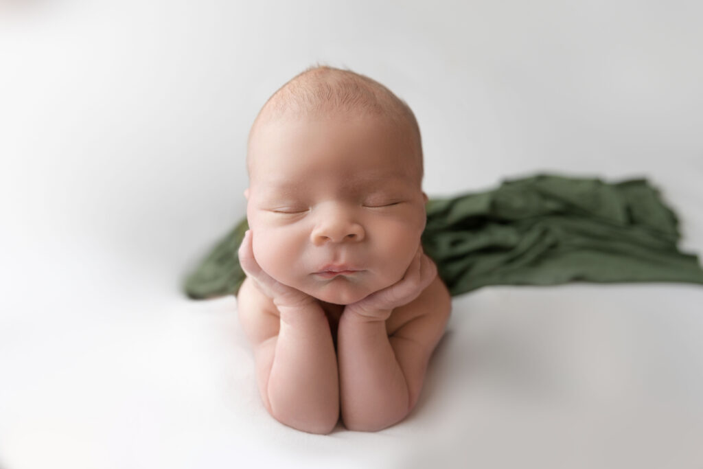 Newborn baby sleeping peacefully on hands. froggy pose