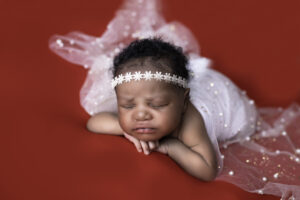 Sleeping baby with white headband on red background