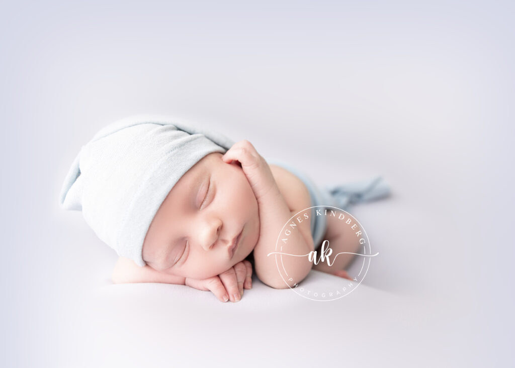 newborn baby sleeping on his side, head tilted resting on his arm, in matching set of hat and wrap