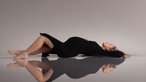 Woman in black dress reclining with reflective surface