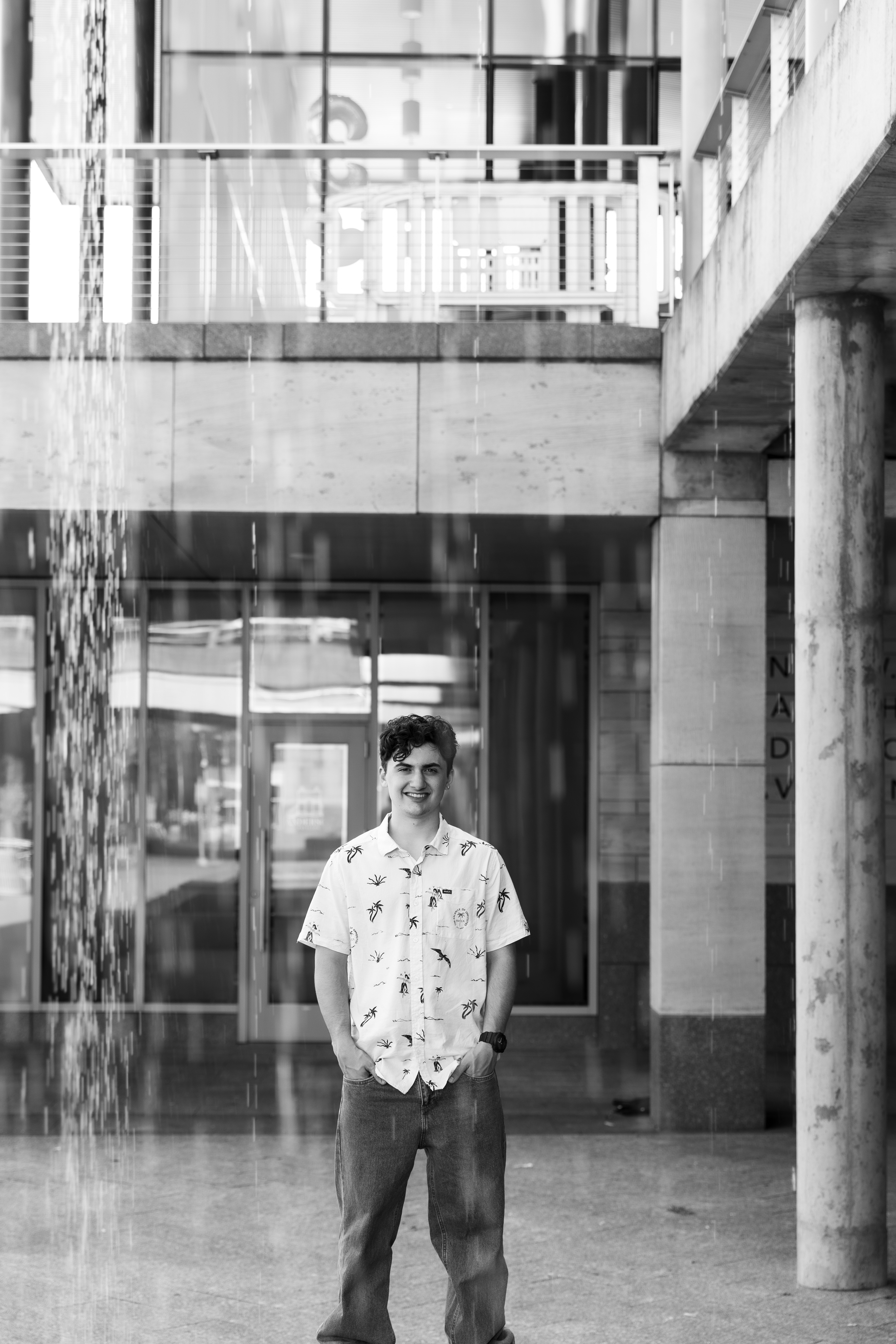 high school senior boy standing behind waterfall in Downtown Cincinnati