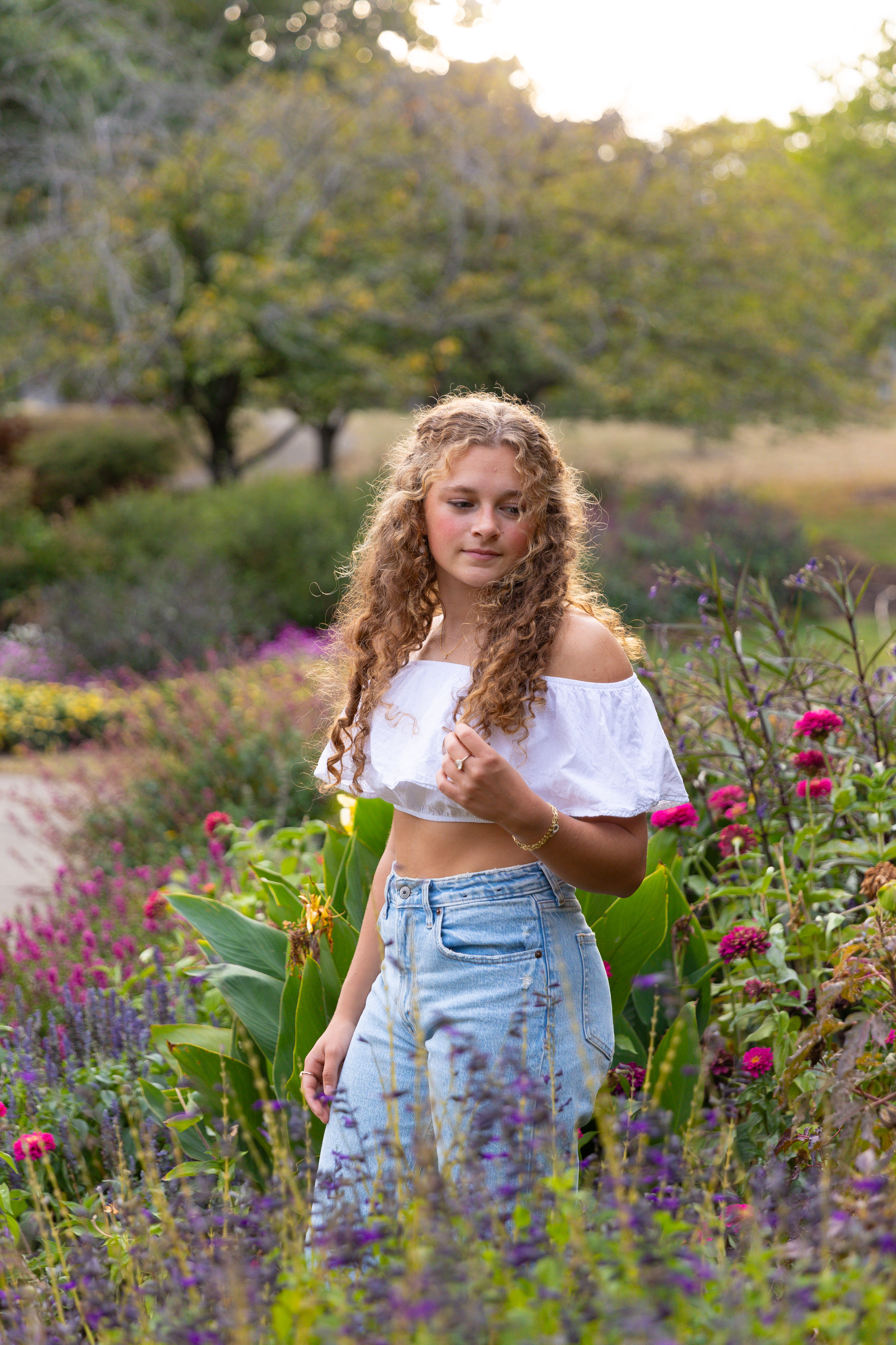 high school senior girl in jeans and white top posing with flowers Eden Park