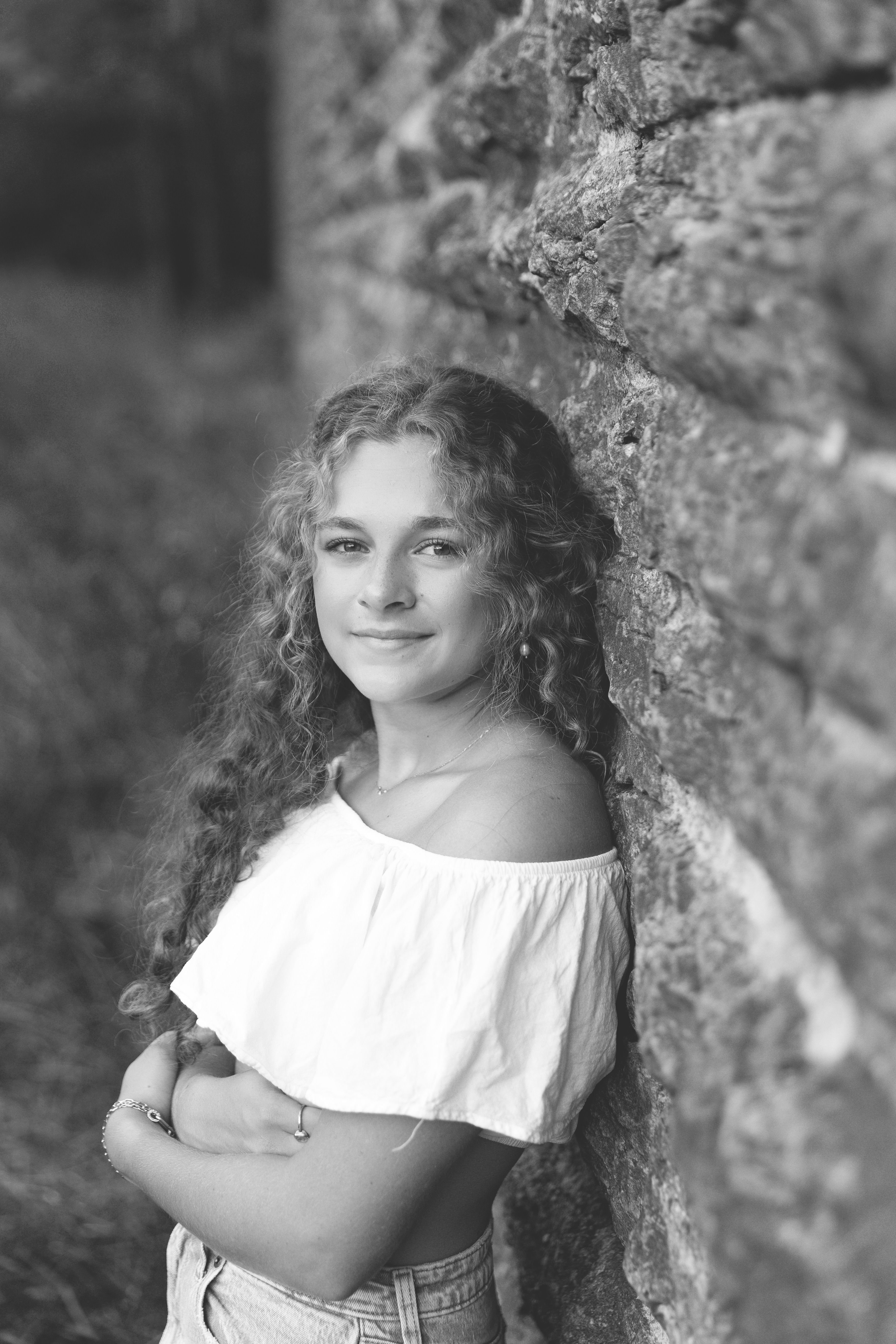 high school girl posing against wall in a white shirt looking at the camera