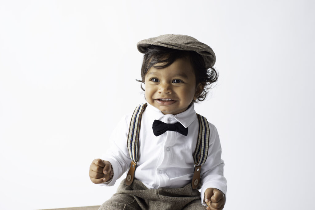 one years old little boy in a hat and bow tie and suspenders