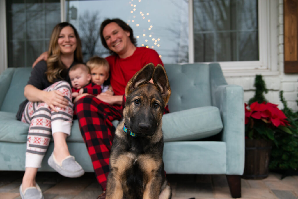 family sitting on couch in front of house with puppy