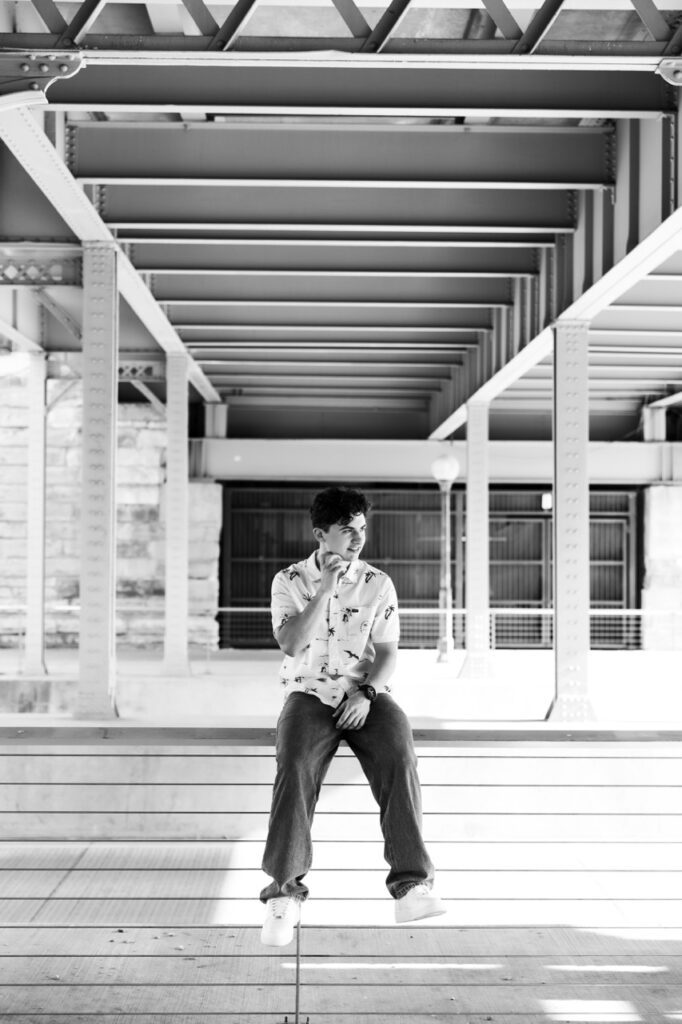 senior session boy sitting on fence Downtown Cincinnati