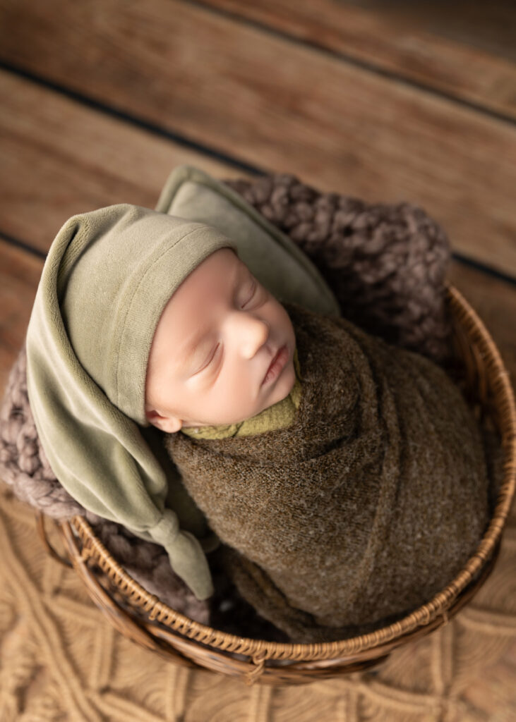 newborn baby wrapped in green sleeping in bucket