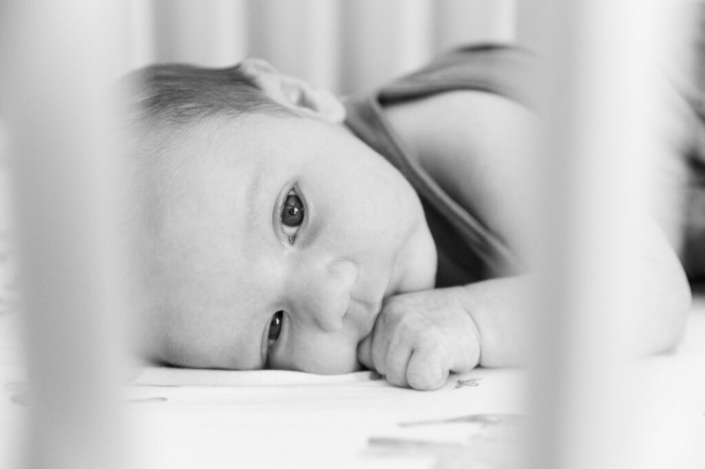 newborn baby boy looking through crib