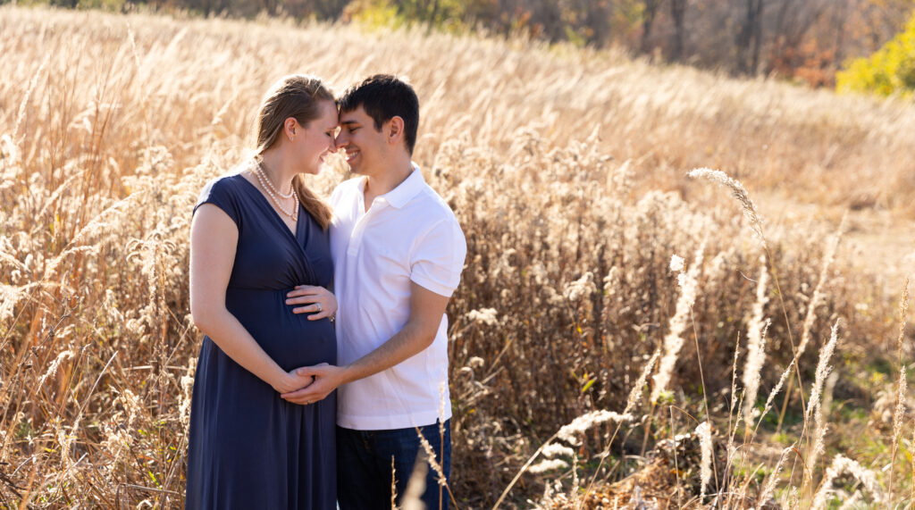 expecting couple posing in the beautiful golden wheat field in French Park