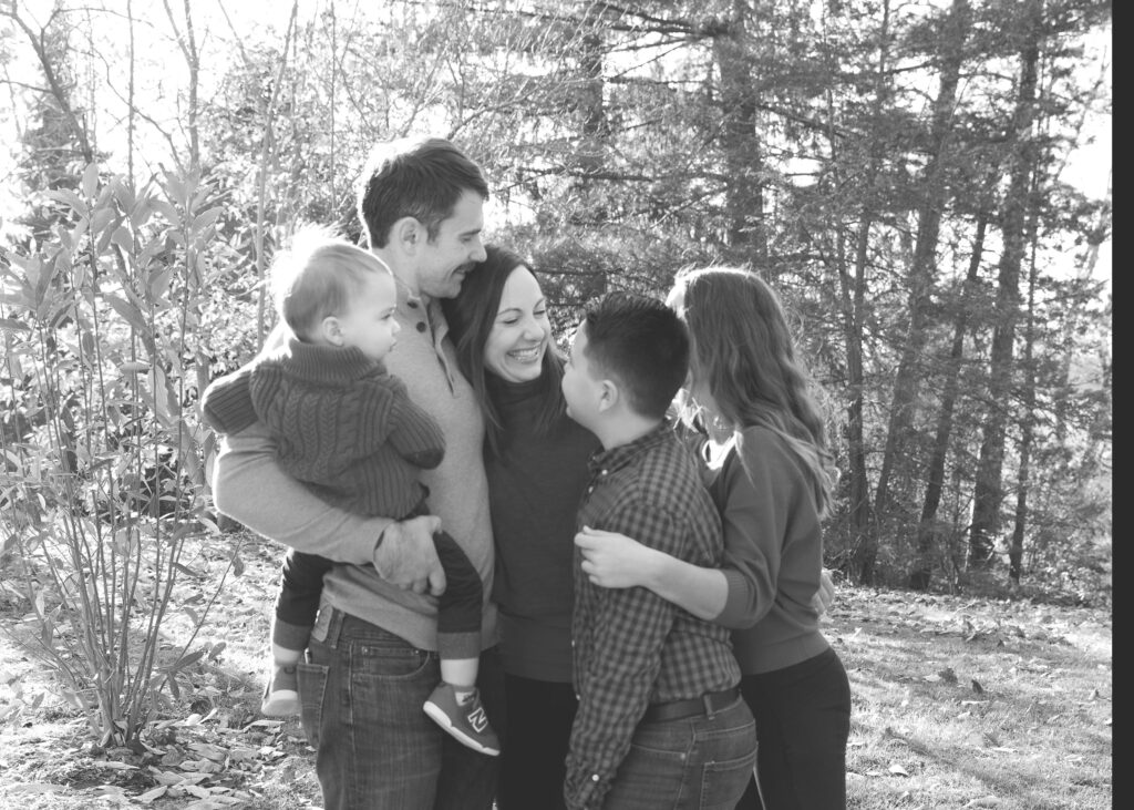 family smiling and hugging in Indian Hill Park in the fall