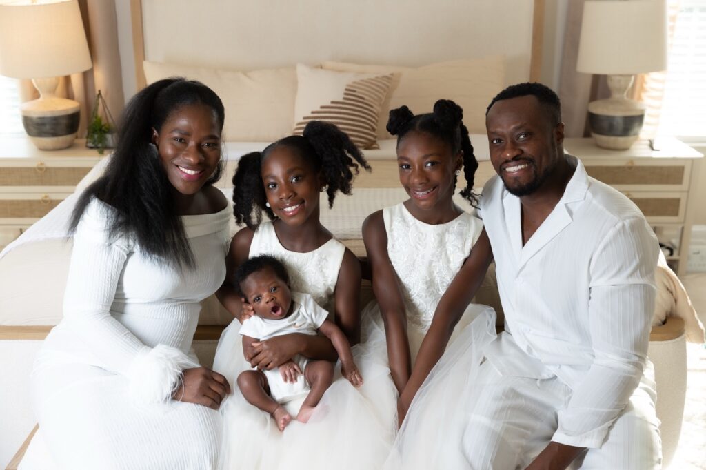 Beautiful african-american family posing with newborn baby and two daughters in their beautiful home