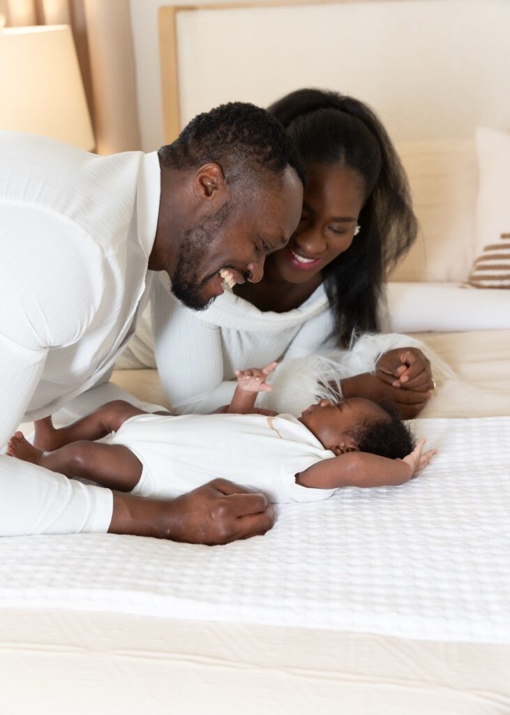 Beautiful african-american mom and dad with newborn baby on bed