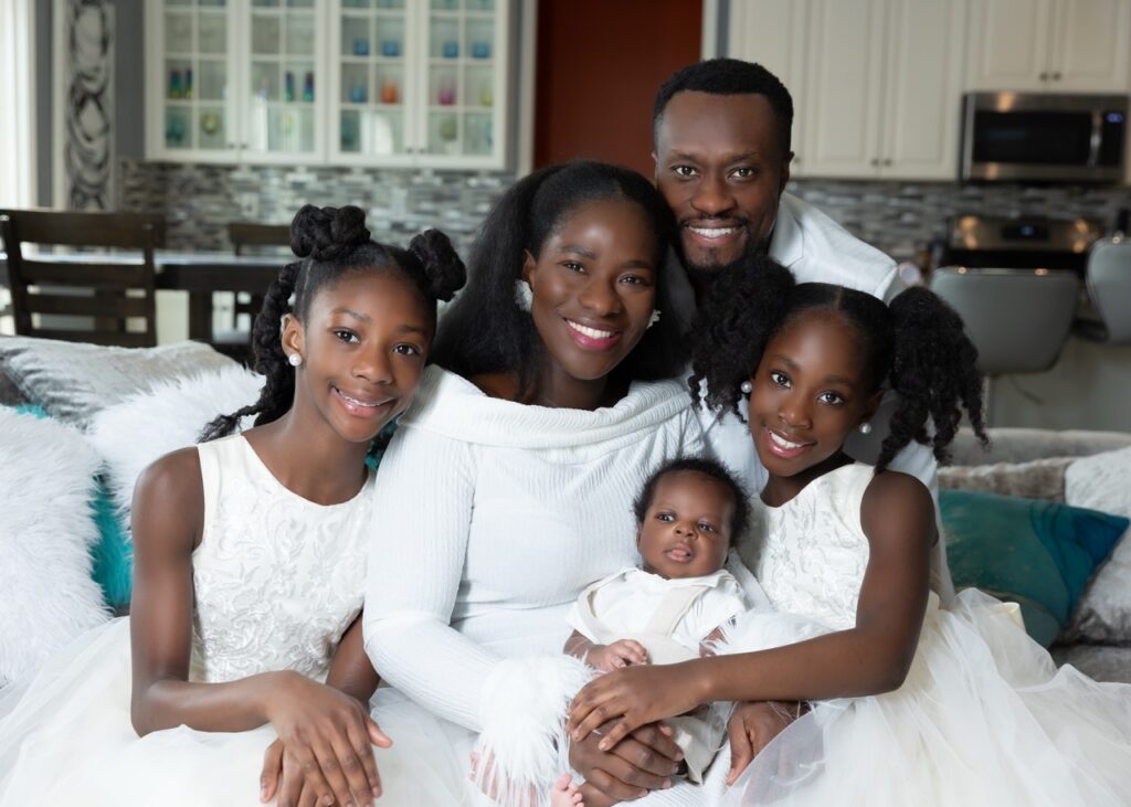 Beautiful african-american family posing with newborn baby and two daughters in their beautiful home