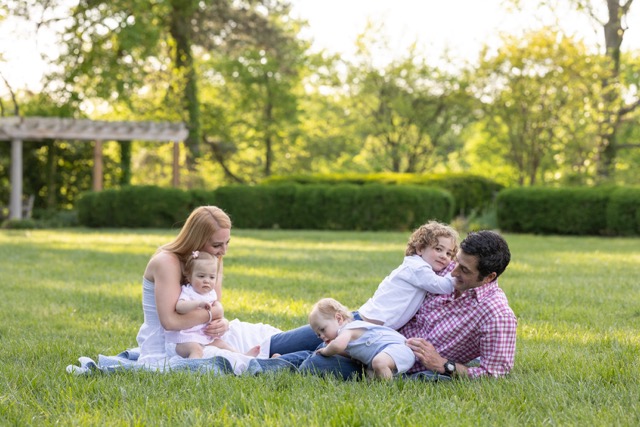 family sitting and playing on a blanket at Ault Park during a photoshoot