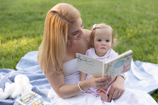 mom reading to toddler girl on a blanket at Ault Park
