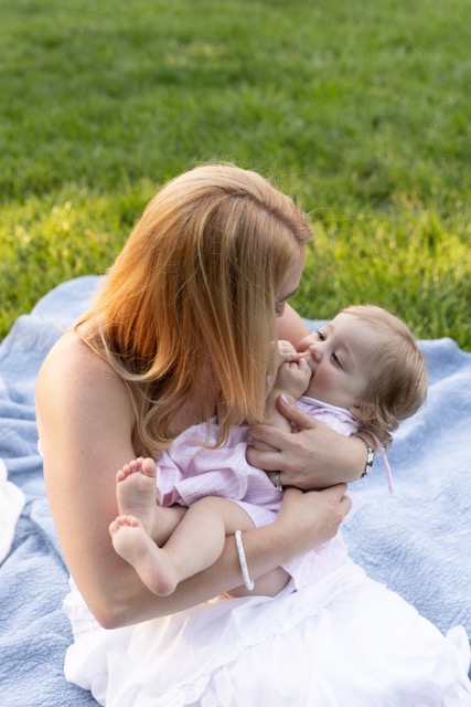 mom holding, playing with baby girl on a blanket at Ault Park