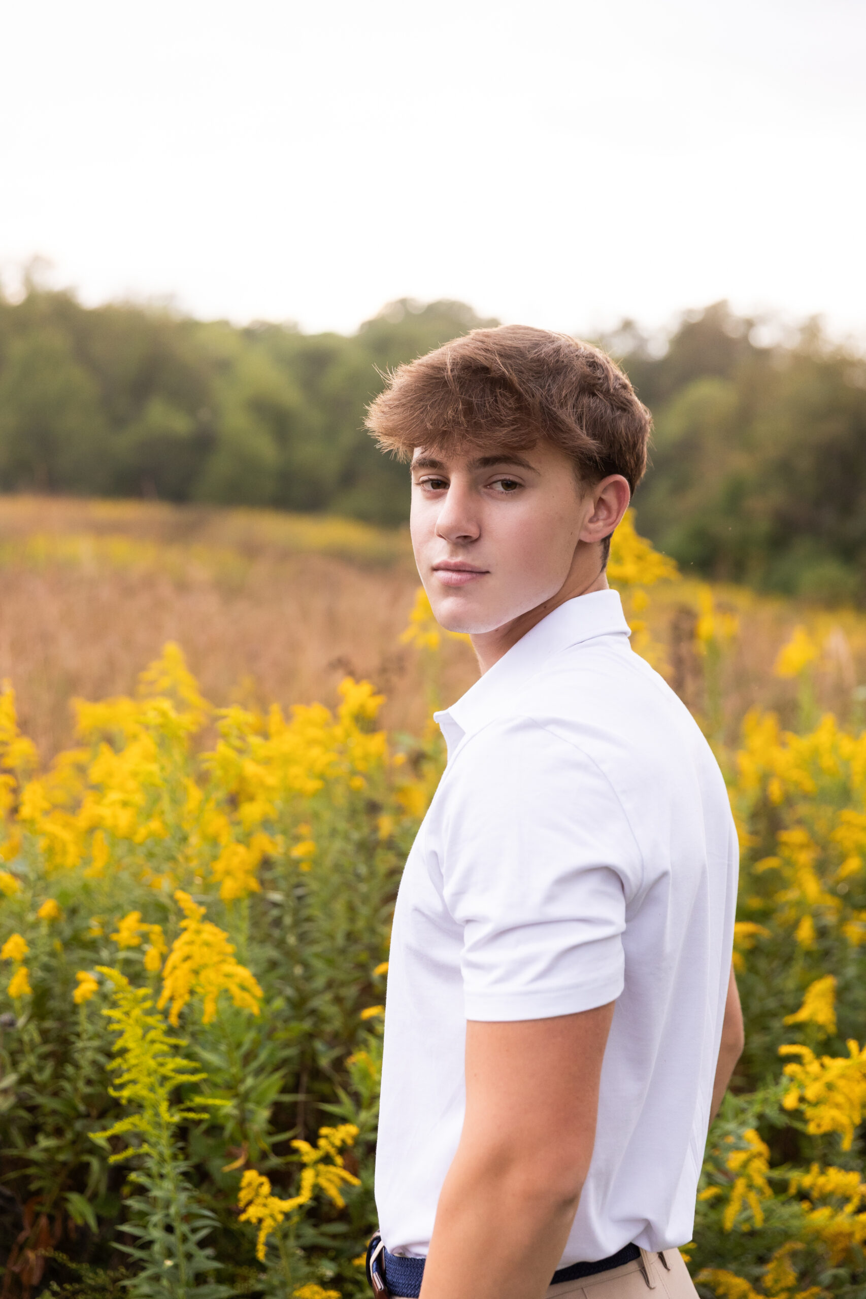young men in white collared shirt, looking over his shoulders with yellow flowers in background at the French Park